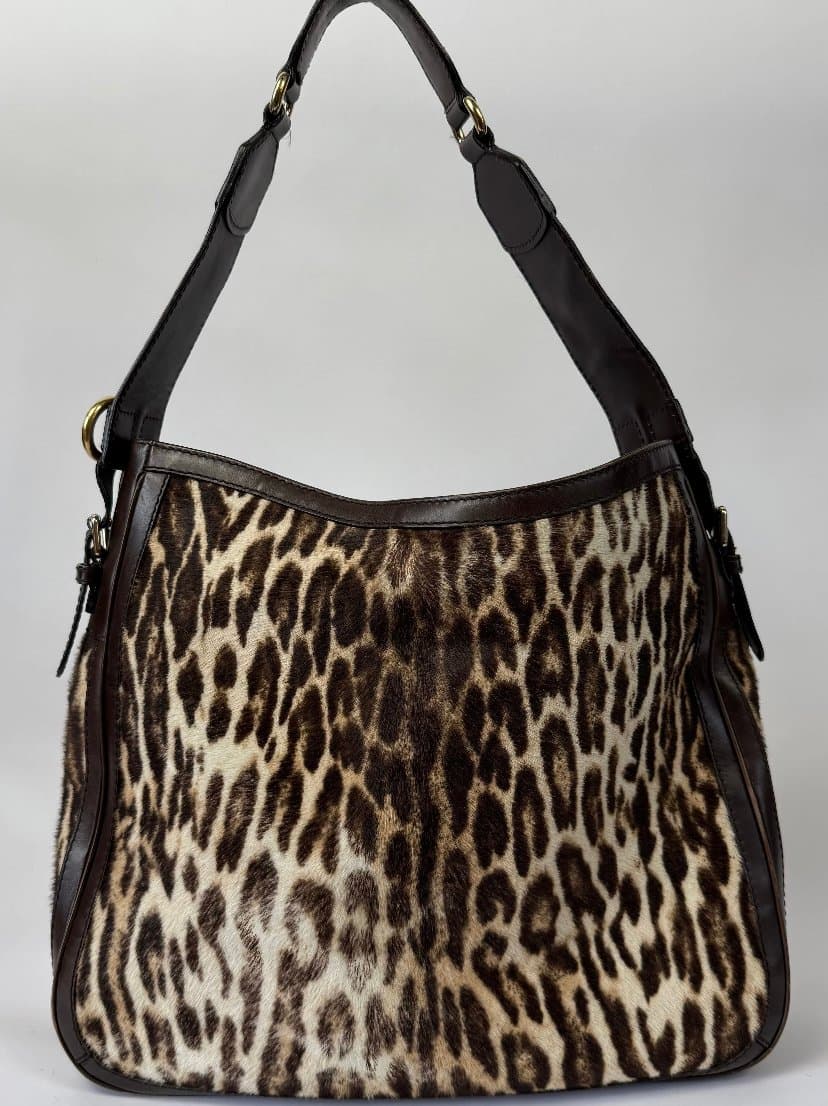 Shoulder bag with leopard-pattern body, dark brown trim and single brown strap with gold-tone hardware, shown from the front